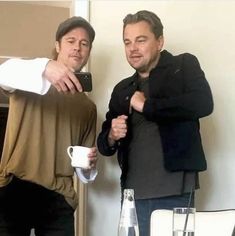 two men standing next to each other holding coffee mugs