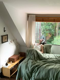 a woman sitting on top of a bed next to a window