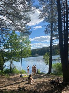 some people are sitting by the water and trees