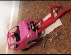 there is a pink toy car and tools on the floor