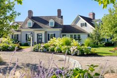 a large white house with lots of flowers in the front yard