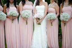 a group of women standing next to each other in pink dresses and holding bouquets