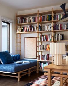 a blue couch sitting in front of a book shelf filled with books