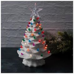 a white ceramic christmas tree with multi - colored lights