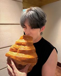 a woman holding a large stack of bread in front of her face and looking at the camera