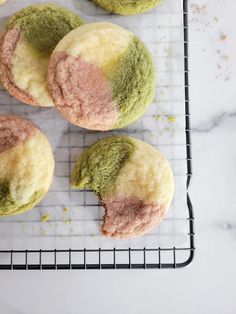 four green and pink cookies on a cooling rack with sprinkles around them