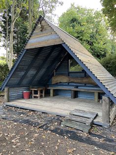 a small wooden structure with benches in the middle of it and a metal roof on top