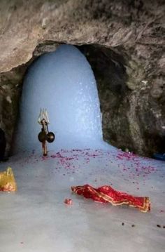 a blue cave filled with lots of red and yellow flowers next to a small statue