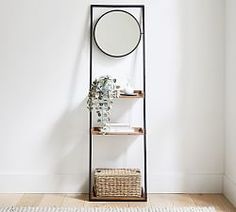 a shelf with a mirror on it next to a basket and a potted plant