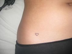 a woman's stomach with a small heart tattoo on it