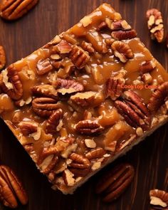 pecan bars are topped with caramel sauce and pecans on a wooden surface