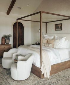 a bedroom with a four poster bed and white furniture on the carpeted flooring