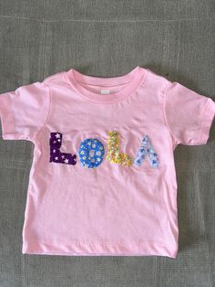 Custom made patchwork tshirts for children, these can be made in several sizes and colours. Names, words, numbers, designs can be embroidered on. Perfect for presents or a special tshirt for parties etc! Pink T-shirt With Name Print For Summer, Summer Pink T-shirt With Name Print, Spring Letter Print T-shirt For Playtime, Cute Pink T-shirt With Letter Embroidery, Cotton T-shirt With Letter Embroidery For Birthday, Pink Fun T-shirt For Playtime, Fun Pink T-shirt For Playtime, Unisex Pink Playful T-shirt, Cute Multicolor T-shirt With Name Print