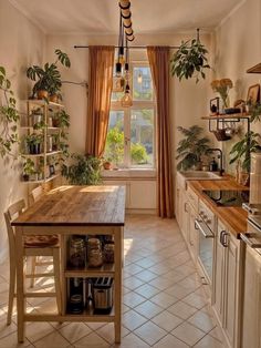 a kitchen with an island in the middle and potted plants on the windowsill