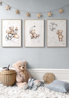 a teddy bear sitting on the floor in front of three framed pictures with stars hanging above it