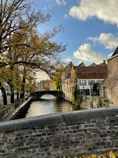 a river running through a small town next to tall brick buildings with trees in the foreground