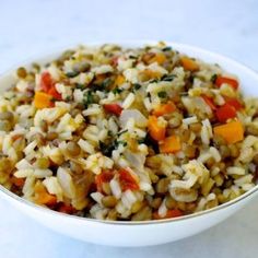 a bowl filled with rice and vegetables on top of a white countertop next to a spoon