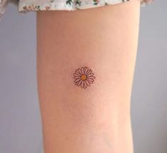 a small daisy tattoo on the ankle is shown in this image, it looks like an orange and yellow flower