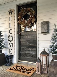 a welcome sign on the front door of a house with christmas trees and lanterns around it