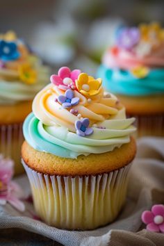 three cupcakes with frosting and colorful decorations