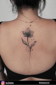 the back of a woman's shoulder with a flower tattoo on it