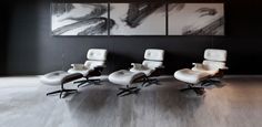 four white chairs are sitting in front of two large black and white paintings on the wall