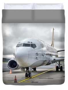 an airplane is parked on the tarmac with orange cones around it and clouds in the background