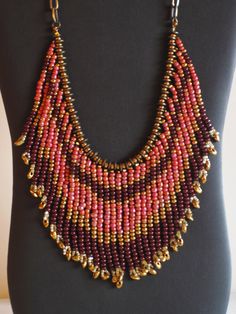 This necklace is made of gold, pink, brown and crystal seed beads. The strands are separated by small brass disks.  It is finished with a bronze chain and toggle closure.  I can adjust the length of the chain if you wish. Bohemian Gold Bib Necklace With Colorful Beads, Bohemian Gold Crystal Necklace With Faceted Beads, Gold Multi-strand Dangling Beads, Unique Gold Beaded Crystal Necklaces, Gold Bohemian Beaded Necklace With Dangling Beads, Bohemian Gold Beaded Necklace With Dangling Beads, Unique Gold Beaded Crystal Necklace, Bohemian Gold Bib Necklace With Round Beads, Bohemian Gold Beaded Necklace With Faceted Beads