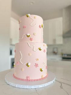 a three tiered pink cake with bees on it