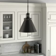 a kitchen with white cabinets and black pendant light hanging from the ceiling over the sink