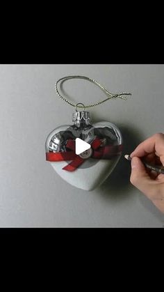 someone is drawing on a heart shaped ornament