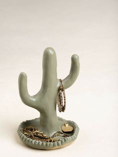 a small cactus with two rings on it's neck and a ring holder in the shape of a cactus