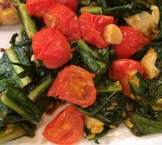 a white plate topped with spinach and tomatoes