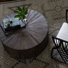 a wooden table with two chairs and a book on top of it next to a plant