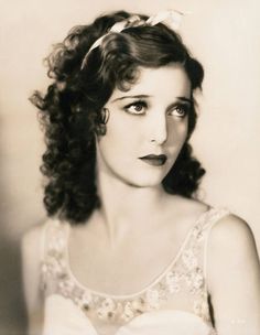 an old black and white photo of a woman with curly hair wearing a bow in her hair