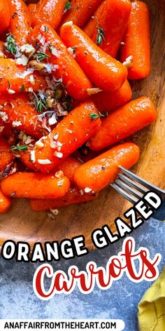 an orange glazed carrots on a wooden plate with a fork and napkin next to it