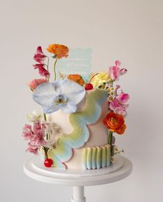 a multi - tiered cake decorated with flowers on a white pedestal