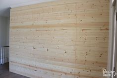 a wooden wall in a room with hard wood flooring and white paint on the walls