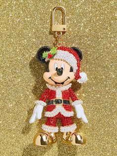 a mickey mouse keychain hanging on a gold glittered background with the word merry written