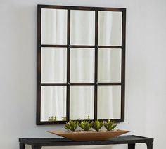 a mirror on the wall above a table with a planter in front of it