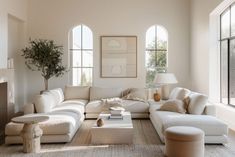 a living room filled with lots of furniture and large windows in the wall behind it