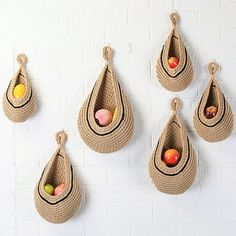 several baskets hanging on the wall with fruit in them and one has an egg inside