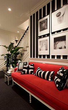 a red couch sitting in the middle of a living room next to a stair case