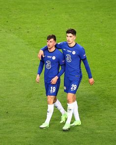 two soccer players are walking on the field