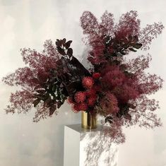 a vase filled with red flowers on top of a white pedestal