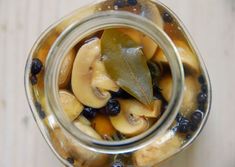 a glass jar filled with sliced fruit and blueberries on top of a wooden table