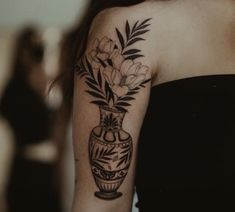 a black and white photo of a woman's arm with flowers in a vase