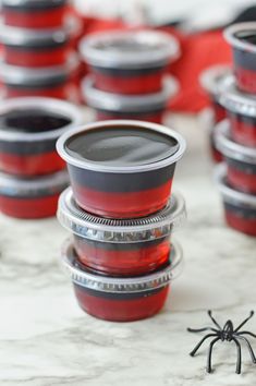 there are many red cups with black rims on the table next to a spider