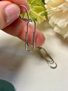 a person holding onto a pair of scissors next to some flowers and a white flower