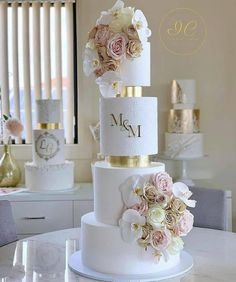 three tiered wedding cake with pink and white flowers on the top, sitting on a table